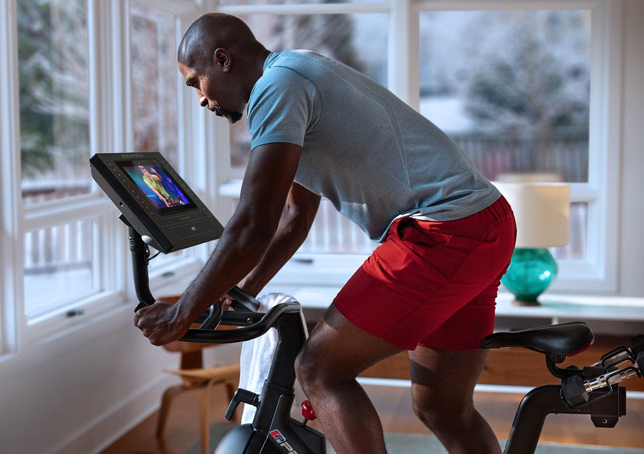 A man riding an exercise bike while looking at the display console.